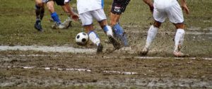 白いユニフォームで試合するサッカー選手